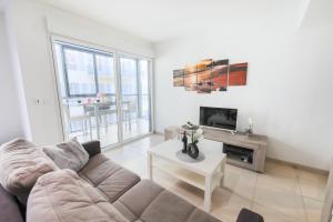 a living room with a couch and a tv at JARDINS MASSENA AP4088 Nice, by Riviera Holiday Homes in Nice