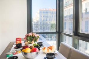 a table with a bowl of fruit and a vase of flowers at JARDINS MASSENA AP4088 Nice, by Riviera Holiday Homes in Nice