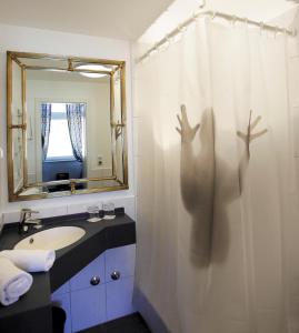 a bathroom with a shower curtain with a persons shadow at Das Krimihotel in Hillesheim