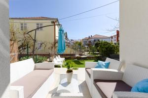 balkon z białymi meblami i niebieskim parasolem w obiekcie Deluxe Apartments Goya w mieście Zadar