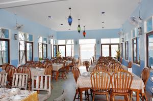 un comedor con mesas, sillas y ventanas en Baanmontra Beach Resort - Bankrut en Ban Krut