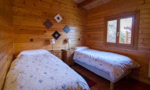 a bedroom with two beds in a log cabin at Paraiso Rural in Villanueva de Cameros