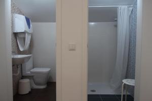 a bathroom with a shower and a toilet and a sink at UAU Hostel in Figueira da Foz