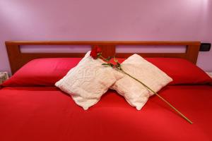 Una cama roja con dos almohadas con flores. en Rio Launaxi Guest House, en Teulada