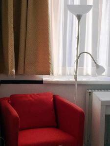 a red chair in front of a window with a lamp at Hotel Gloria Budapest City Center in Budapest