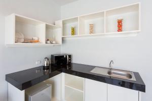 a kitchen with white cabinets and a black counter top at PJ Patong Resortel in Patong Beach