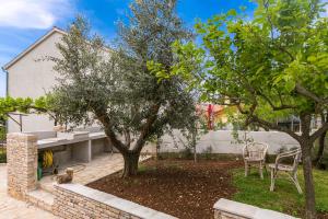 a garden with a tree and two chairs in front of a building at Elvira in Medulin