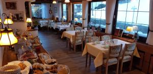 ein Restaurant mit weißen Tischen und Stühlen und Fenstern in der Unterkunft Landhaus Eickler in Baiersbronn