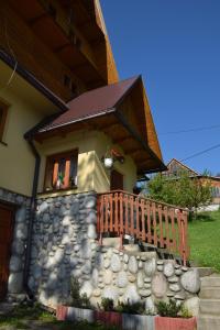 a house with a stone wall and a wooden porch at Na ubocy in Brzegi