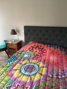 a bed with a colorful comforter on top of it at La Luterne in Villaines-les-Prévôtes