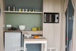 a small kitchen with a table and a microwave at Camping le Rouge Gorge **** 10' Puy du Fou in Saint-Laurent-sur-Sèvre