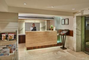 um homem a falar ao telefone no átrio de um hotel em Hotel Bawa Continental em Mumbai