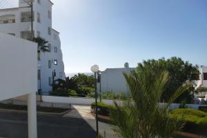 a building with a street light and a palm tree at Calle Hesperides in Costa Del Silencio
