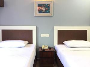 um quarto com duas camas e um telefone sobre uma mesa em CK Hotel em Malaca