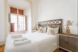een witte slaapkamer met een groot bed met handdoeken erop bij FLH Rossio's Flat in Lissabon