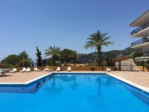 a large swimming pool with chairs and a building at STUDIOS FACE À LA MER - Cala Llevado in Tossa de Mar