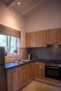 cocina con armarios de madera, fregadero y ventana en Avali luxury houses en Gaios