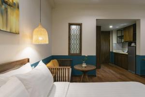 ein Schlafzimmer mit einem Bett und einem Tisch sowie eine Küche in der Unterkunft Casa Rosa Apartment in Đà Nẵng