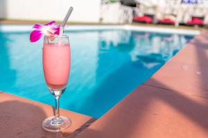 a drink with a flower in a glass next to a swimming pool at PJ Patong Resortel in Patong Beach