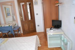 a room with a bed and a desk with a television at Villa Verde Apartments and Rooms in Premantura