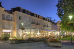 um edifício com uma estufa em frente em SEETELHOTEL Pommerscher Hof em Heringsdorf