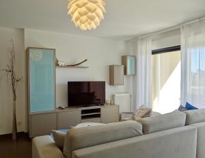 a living room with a white couch and a television at Ô de Mer at My Luxury Home in Provence in La Ciotat