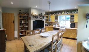 a kitchen with a wooden table and a kitchen with yellow cabinets at Watersedge in Mulranny