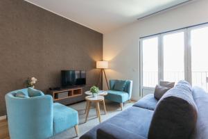 een woonkamer met een bank, 2 stoelen en een tv bij FLH Restauradores Modern Apartment in Lissabon