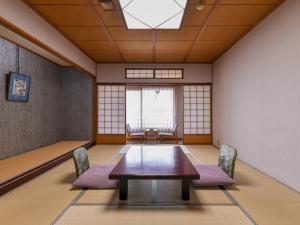 Habitación con mesa, sillas y ventana en Awara Onsen Minoya Taiheikaku, en Awara