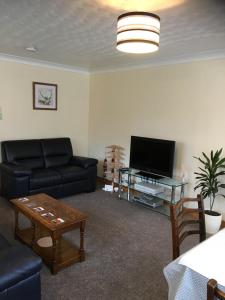 a living room with a couch and a tv at Treetops Bungalow Loch Ness in Drumnadrochit