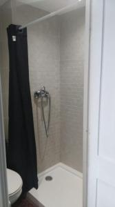 a shower with a black shower curtain next to a toilet at Roman Circus views Apartment in Tarragona