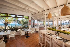 Un restaurante con mesas y sillas y el océano. en Grupotel Orquidea, en San Agustín