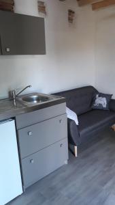a kitchen with a sink and a couch in a room at Pigeonnier Brens in Brens