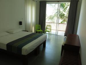 a hotel room with a bed and a balcony at Villa Beach Road Ambalangoda in Ambalangoda