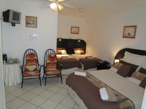 a hotel room with two beds and two chairs at Blue Horizon Bay Guest House in Van Stadensriviermond