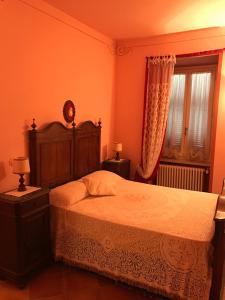 een slaapkamer met een bed met een houten hoofdeinde en een raam bij B&B Cantine Pietronero in Orsara Bormida