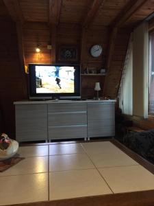 a living room with a flat screen tv on a dresser at Domek Letniskowy in Mrzeżyno