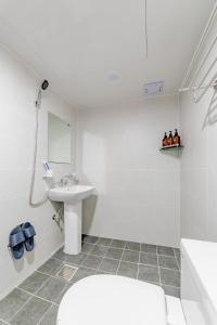 La salle de bains blanche est pourvue d'un lavabo et de toilettes. dans l'établissement Guesthouse Dear Moon, à Busan