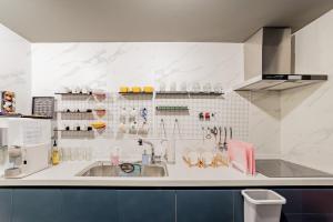 a kitchen with a sink, refrigerator, and dishwasher at Guesthouse Dear Moon in Busan