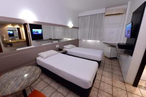 a hotel room with two beds and a television at Panorama Tower Hotel in Ipatinga