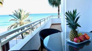 a table with a bowl of fruit on a balcony with the beach at Meerblick Apartment Sabina in Cala Millor