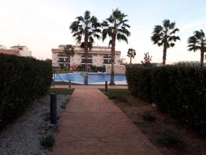 a walkway leading to a building with palm trees at Chalet adosado 3 dormitorios in Sant Jordi