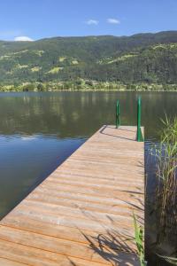 a wooden dock on a lake with a view at Pension Strauß in Ossiach