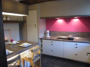 a kitchen with a table and a pink wall at La Romaine in Durbuy