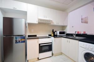 a kitchen with white cabinets and a stainless steel refrigerator at KeyHost - Deluxe Studio - Dubai Sports City - K241 in Dubai