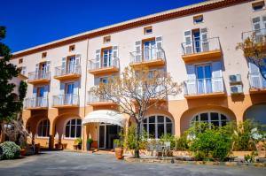 een appartementencomplex met balkons en een binnenplaats bij Hôtel les Arbousiers in Calvi