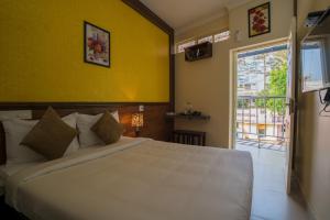 1 dormitorio con cama blanca y pared amarilla en Gems 9 Airport Hotel, en Kochi