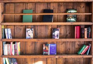 una mensola in legno piena di libri di Langley Hotel La Vieille Ferme a La Salle-les-Alpes