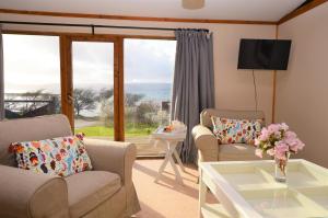 sala de estar con 2 sillas, mesa y ventana en Clamshell Lodge, en Otter Ferry