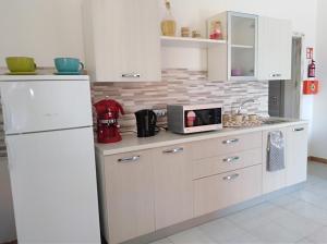 cocina con nevera blanca y microondas en B&B Le Peonie, en Badesi